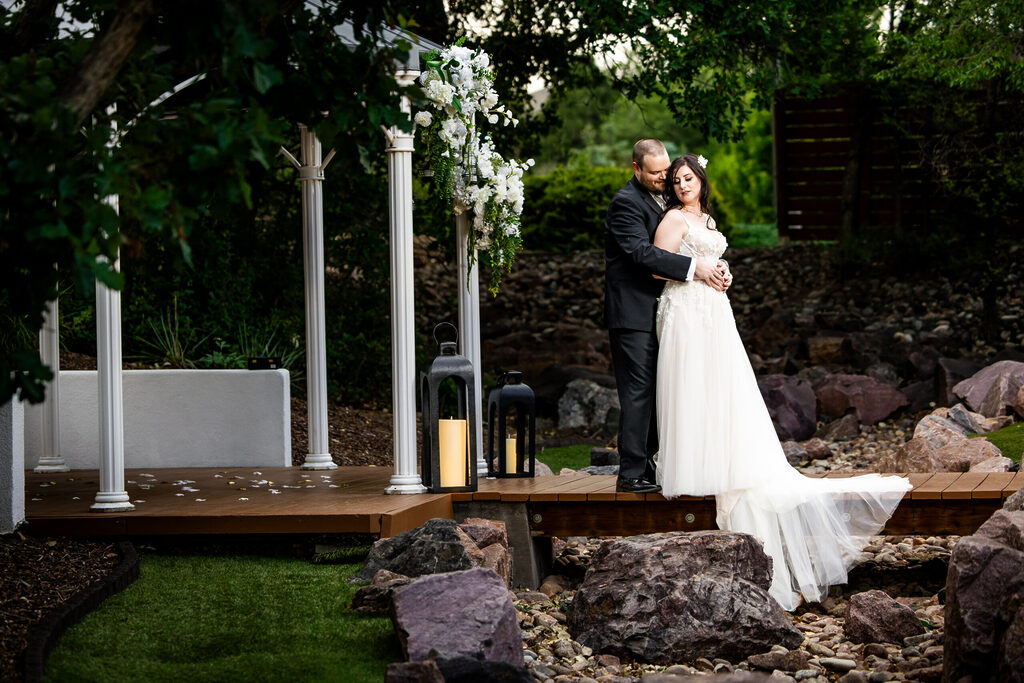 Bride and Groom standing on a bridge across a stream with trees behind them Colorado Wedding Photographer Colorado Wedding Photographer