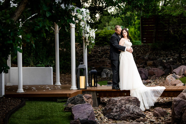 Bride and Groom standing on a bridge across a stream with trees behind them Colorado Wedding Photographer Colorado Wedding Photographer