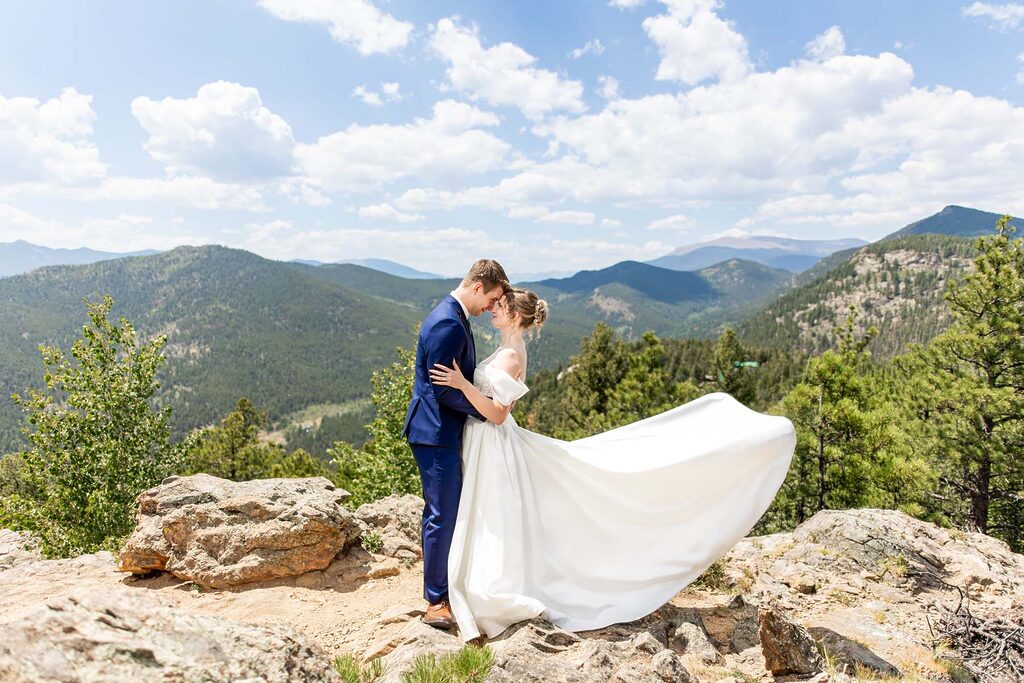 Bride and groom kiss on a rocky overlook with distant mountains under a blue sky Colorado Wedding Photographer Colorado Wedding Photographer
